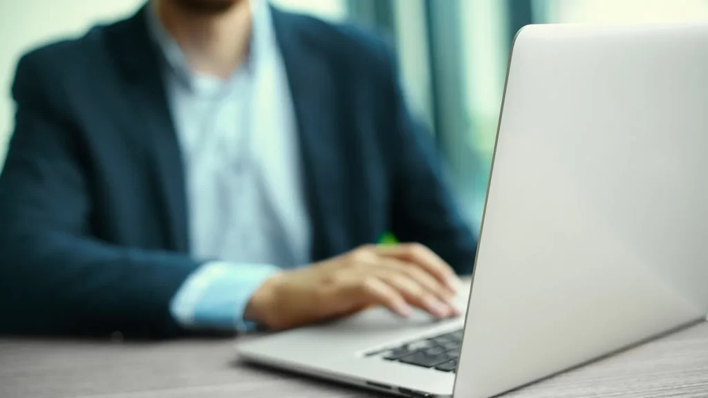 Mani di un uomo in giacca che lavora al portatile in ufficio