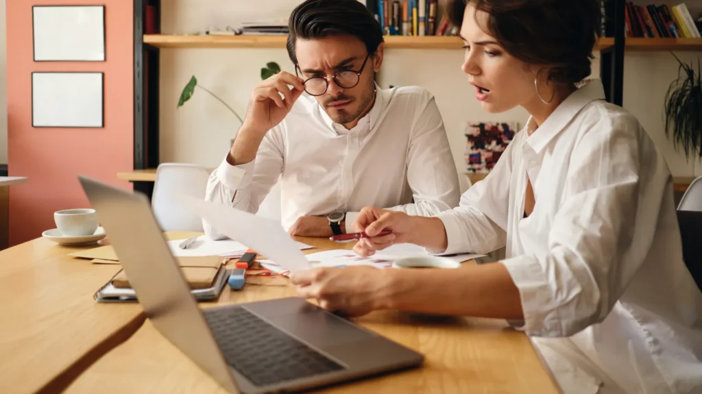 Titolare d'azienda e consulente esaminano un preventivo al tavolo con un portatile aperto